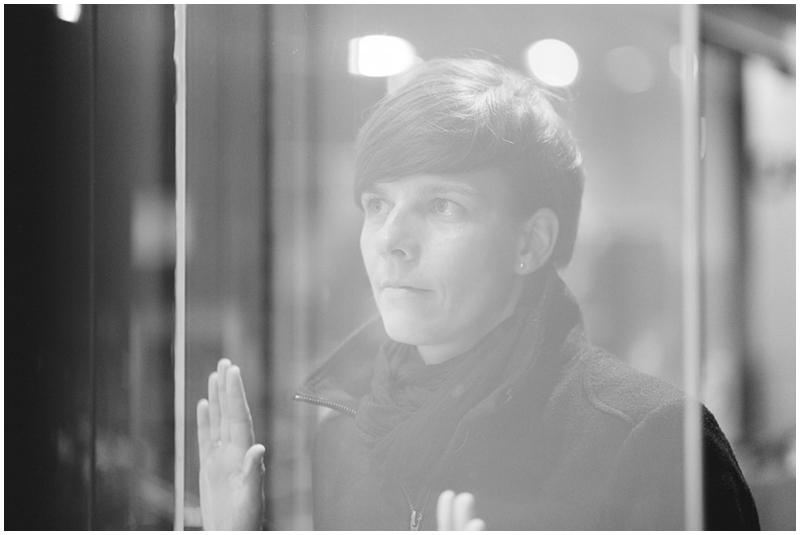 portrait einer frau durch ein schaufenster in monochrom fotografiert von anne juengling